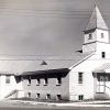 Multistory building with square bell tower and covered porch