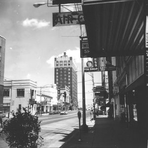 Multistory buildings with neon signs and other signs on two-lane city street