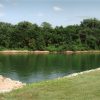 River with trees on opposite shore and rocky shoreline in foreground