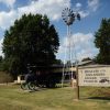 Single-story building with steam tractor on display and windmill "Museum of the Arkansas Grand Prairie"