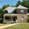 Two-story brick house with covered porch and yard and trees