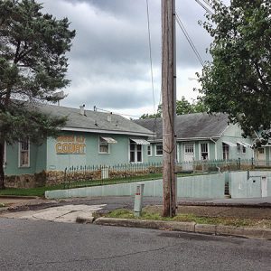 Single-story pale blue-green apartment buildings on street