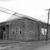 Brick gymnasium building with Dutch gable roof and arched entrances