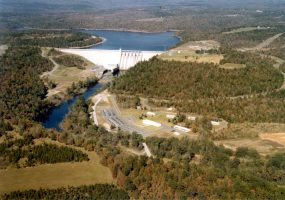 Aerial view of lake and concrete dam with trees and countryside in the background