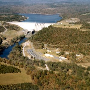 Aerial view of lake and concrete dam with trees and countryside in the background