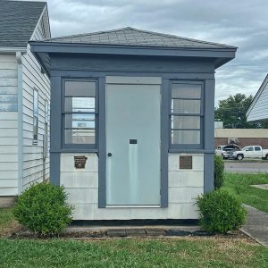 Blue and white guard house next to single-story building with white siding