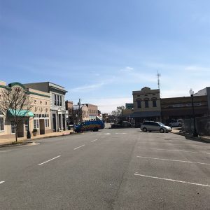 Town buildings and storefronts on paved streets with parked cars