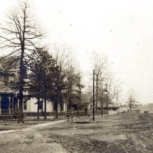 Dirt road with houses, trees, and telephone poles