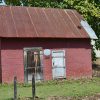 Small brick building with two doors and rusted metal roof