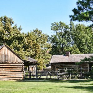 two log cabins facing each other across fenced-in yard