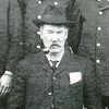 Older white man in suit and hat smoking a pipe