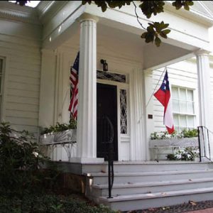 Wood frame home classical front porch American flag left and Confederate national flag Stars and Bars right