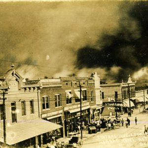 Burning brick buildings on street with smoke filling the sky