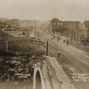 Destroyed buildings on city street with people milling about