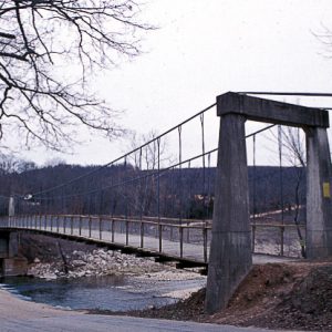 Suspension foot bridge over river as seen from road beside it