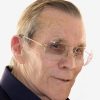 Old white man with glasses smiling in collared shirt