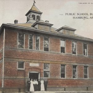 Red brick building with cupola with people standing before it