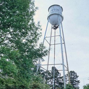 Tall white water tower as seen looking up from the ground