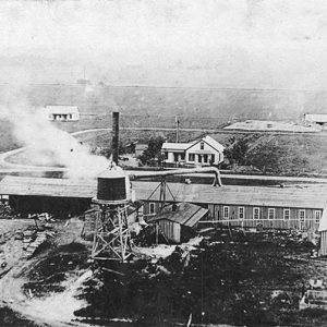 Aerial view of house and factory buildings with water tower