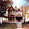 Two-story house with ornate porch and autumn foliage