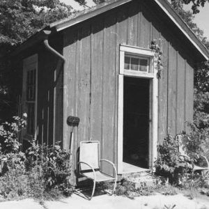 Pair of chairs outside small building with open door