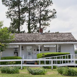 Single-story house with white fence and trees