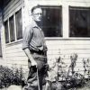 White man with cane and dog standing outside at corner of a house