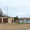 Two metal buildings with garage bay doors on gravel parking lot