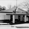 Single-story storefront "Harvey's Grocery" with ice cooler and dr. pepper machine