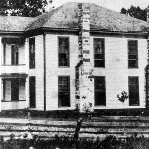 Two-story building with four columns in front and brick chimneys