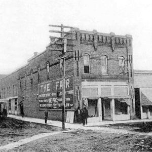 Street with brick buildings and telephone poles with people walking on the sidewalk