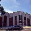 Multistory brick building with flag pole on parking lot