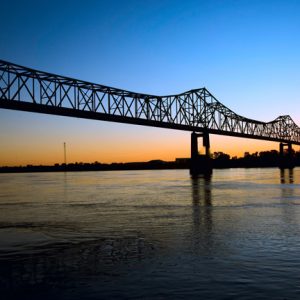 Steel cantilever bridge over river at sunset