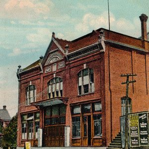 Multistory brick building with arched top story windows and awning on sidewalk