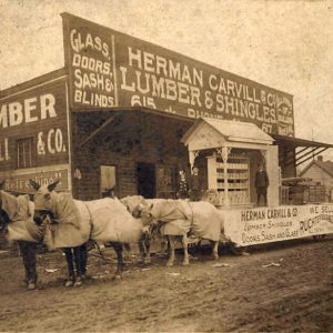 Horse drawn parade float outside "Herman Carvill and company lumber and shingles" store