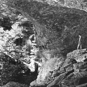 Man standing on rock outcrop above waterfall