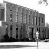 Multistory art deco brick building with carved stone bordered entrance steps landscaping and light pole