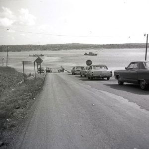 Cars on road leading to lake and ferry across it