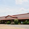 Metal sided building and bushes on gravel parking lot