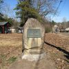 Historical marker plaque on large rock in yard next to street