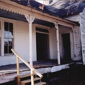 Abandoned house with covered porch and white siding