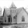 Single-story church building with central bell tower and arched windows