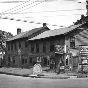 Two-story building with signs and historical marker on street corner