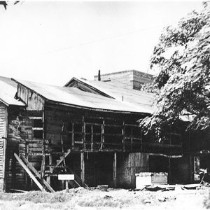 Dilapidated two-story building with damaged balcony and covered walkway