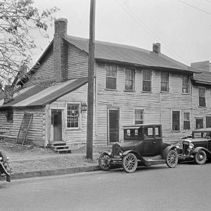 Cars parked outside two-story building with brick chimney