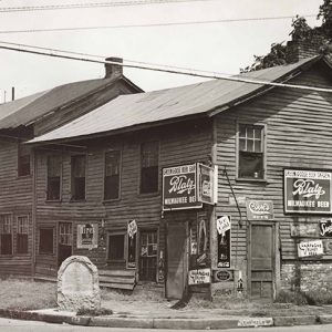 Run down two-story building with brick chimneys and historical marker on street corner