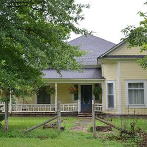 Yellow house with covered porch and fence