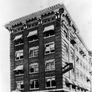 multistory building on street corner with sign saying "Hollenberg Music Co." on first floor