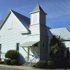 Single-story white building with covered porch and bell tower