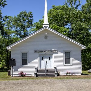 Single-story church building with white siding and steeple on its roof